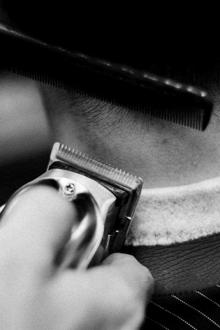 Detailed shot of a barber using clippers and comb during a haircut.